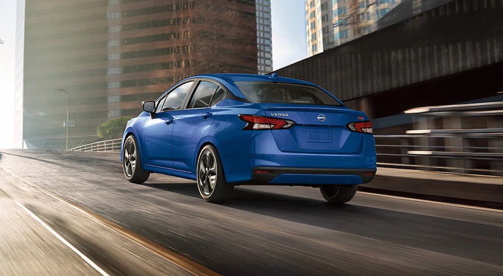 A blue 2024 Nissan Vera SR is driving up a highway ramp.