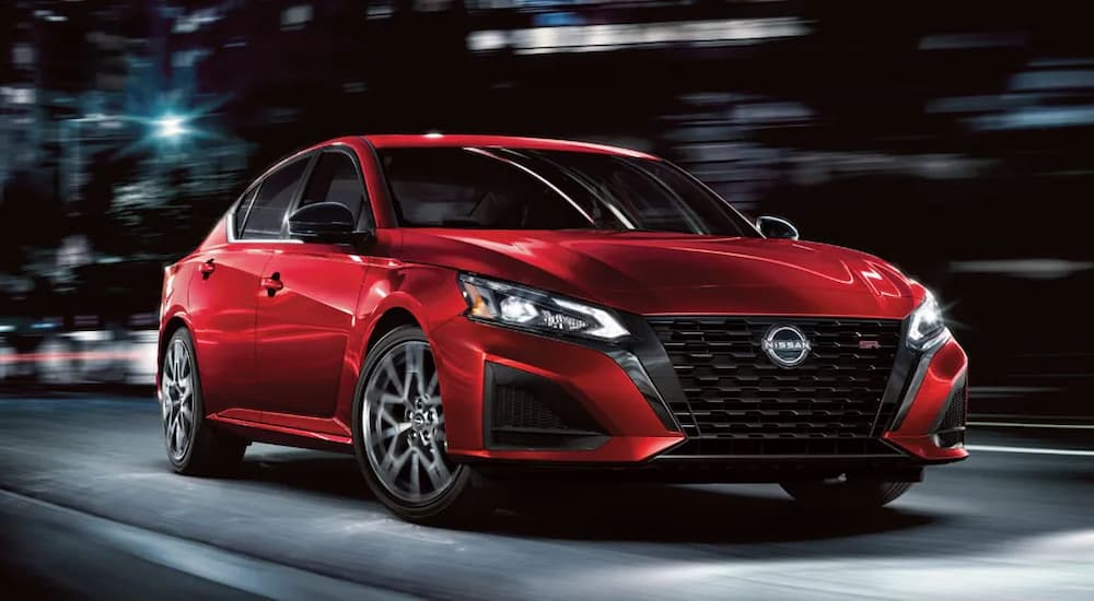 A red 2024 Nissan Altima SR VC-Turbo is driving on a city street at night.