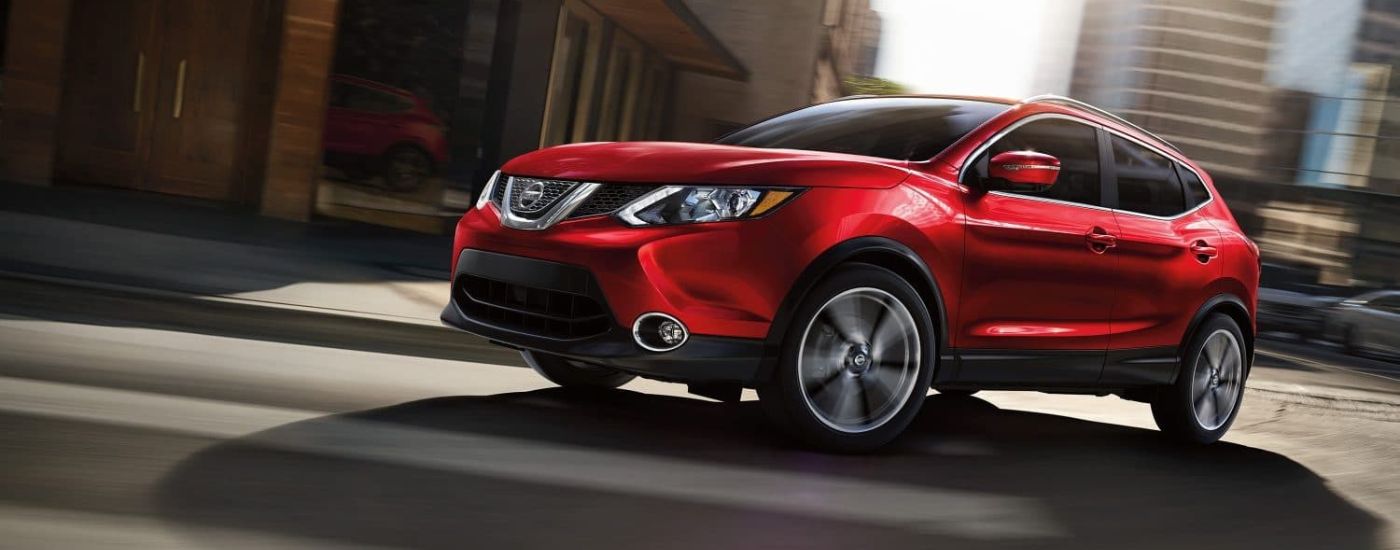 A red 2019 Nissan Rogue Sport is shown driving on a city street.