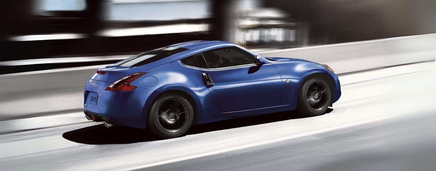 A blue 2020 Nissan 370Z is shown from the side driving over a bridge.