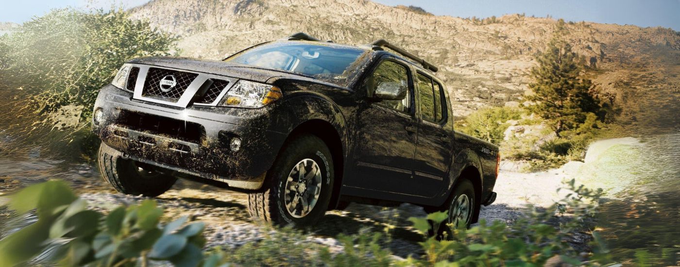 A black 2019 Nissan Frontier PRO-4X is shown driving on a trail after visiting Nissan dealer near you.